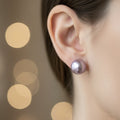 Close-up of an ear wearing a purple pearl earring with a blurred background