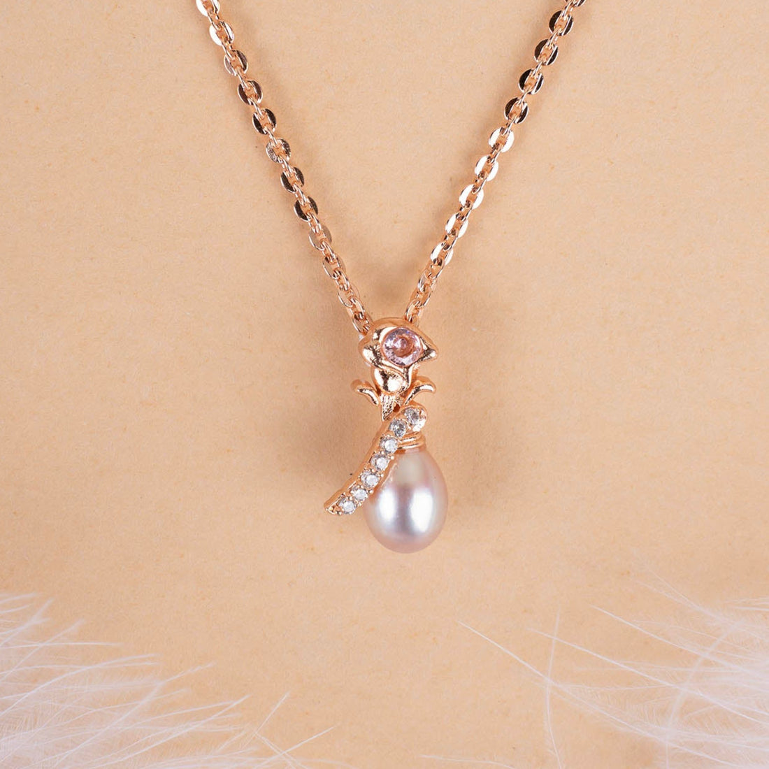 Rose gold necklace with a pearl pendant on a beige background