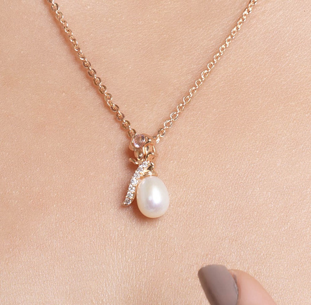 Rose gold necklace with a pearl pendant on a beige background