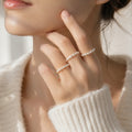 A close-up lifestyle shot of a model wearing three delicate pearl bead rings on her fingers, paired with a soft cream-colored knit sweater.