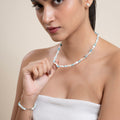 Woman wearing a beaded necklace and bracelet on a beige background