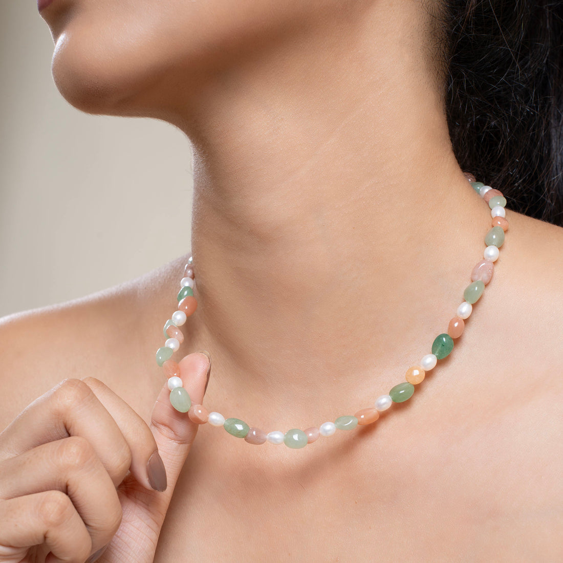 Woman wearing a pearl necklace and bracelet against a neutral background