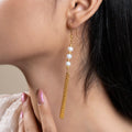A women wearing a triple pearl tassel earring with gold-colored metal details.