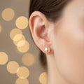 Close-up of an ear wearing a pearl earring with a blurred gold background