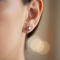 Close-up of an ear wearing a silver earring with a blurred background