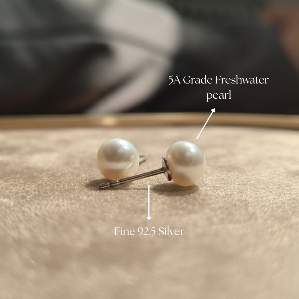 Pearl earrings with silver posts on a textured surface, labeled as 5A Grade Freshwater pearls and Fine 92.5 Silver.